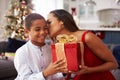 Mother Giving Christmas Presents To Son At Home