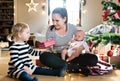 Mother giving daughter Christmas present, holding her son. Royalty Free Stock Photo