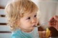 Mother giving healthy food to her adorable child at home. Feeding kids. Royalty Free Stock Photo