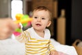 Mother giving her little daughter toy, playing with baby toddler girl, mom enjoying child care, sitting on bed Royalty Free Stock Photo