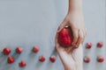 Mother giving her son a big red strawberry. Little boy taking a strawberry from mom`s hand. Little strawberries on bright blue Royalty Free Stock Photo