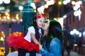Mother giving a kiss to smiling daughter at night in the city