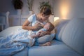 Young mother giving milk to her hungry baby at night Royalty Free Stock Photo