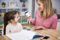 Young mother giving pills to her daughter while doing homework Royalty Free Stock Photo