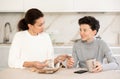 Mother giving some cash and instructions her teenager son sitting at home Royalty Free Stock Photo