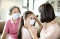 Mother and grandmother help daughter wearing face mask to prevent  air pollution and COVID-19 coronavirus Royalty Free Stock Photo