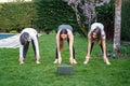 Mother, grandmother and teen daughter practicing fitness lesson online outdoors in garden