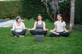 Mother, grandmother and teen daughter practicing online yoga class outdoors Royalty Free Stock Photo