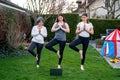 Mother, grandmother and teen daughter practicing online yoga lesson outdoors in garden at quarantine