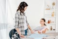mother in grey shirt and daughter in pink t-shirt with clothes standing near ironing board