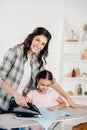 mother in grey shirt and daughter in pink t-shirt ironing