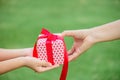 Mother hand giving a gift box with red ribbon to her child Royalty Free Stock Photo