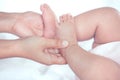 Mother hand holding little baby girl feet while she lying on bed Royalty Free Stock Photo