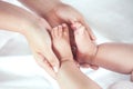 Mother hand holding little baby girl feet while she lying on bed Royalty Free Stock Photo