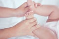 Mother hand holding little baby girl feet while she lying on bed Royalty Free Stock Photo