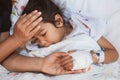 Mother hand holding sick daughter hand who have IV solution bandaged with love and care while she is lying down on bed Royalty Free Stock Photo