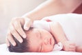 Mother hand touching asian newborn baby girl head