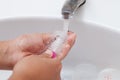 Mother hand washing baby plastic nipple on white sink Royalty Free Stock Photo