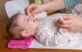 Mother hands cleaning eyes of baby with cotton