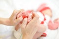 Mother hands with red nails holding newborn baby legs. Royalty Free Stock Photo