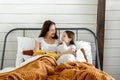 Mother and happy little preschool daughter reading book in cozy bedroom at home Royalty Free Stock Photo