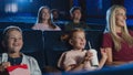 Mother with happy small children in the cinema, watching film.