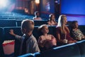 Mother with happy small children in the cinema, watching film.