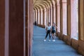 Mother with hat and daughter with hand on her hip standing in portico i