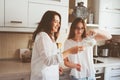 Mother having breakfast with teen daughter at home in modern white kitchen