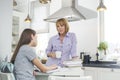 Mother having coffee while looking at daughter studying in kitchen Royalty Free Stock Photo