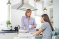 Mother having coffee while looking at daughter studying in kitchen Royalty Free Stock Photo