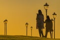 A mother in a headscarf goes home with her daughter in the evening before sunset and calls her father to put a kettle on for tea.