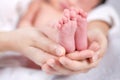 The mother held the baby in her hand. Mom holding small baby feet. Woman hands holding newborn baby feet