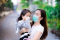 Mother held daughter warmly in order to maintain social distance in public area.