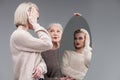 Attentive blonde woman refreshing her bob haircut in round mirror