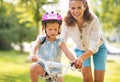 Mother helping baby girl riding on bicycle Royalty Free Stock Photo