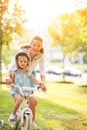 Mother helping baby girl riding bicycle in park Royalty Free Stock Photo