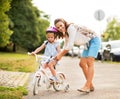 Mother helping baby girl riding bicycle Royalty Free Stock Photo