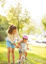 Mother helping baby girl riding bicycle Royalty Free Stock Photo