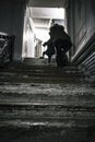 Mother helping baby to climb long stairs on a dark old building,