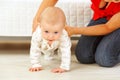 Mother helping cheerful baby learn to creep Royalty Free Stock Photo