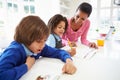 Mother Helping Children With Homework In Kitchen Royalty Free Stock Photo