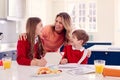 Mother Helping Children In School Uniform Doing Homework At Kitchen Counter Royalty Free Stock Photo