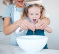 Mother helping daughter crack egg into bowl while baking together in the kitchen. Mother and daughter baking together Royalty Free Stock Photo