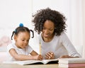 Mother helping daughter do homework in workbook Royalty Free Stock Photo