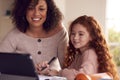 Mother Helping Daughter With Homework Sitting At Kitchen Counter Using Digital Tablet Together Royalty Free Stock Photo