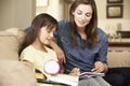 Mother Helping Daughter With Homework Sitting On Sofa At Home Royalty Free Stock Photo