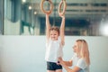 Mother helping daughter to play sports on gymnastic rings Royalty Free Stock Photo