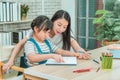 Mother helping her daughter doing creative art homework coloring pencil book at home for family togetherness concept