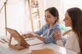 Mother helping her daughter with homework using tablet at home Royalty Free Stock Photo